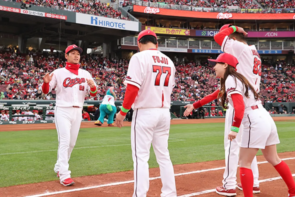 マツダスタジアムのグラウンドで、広島東洋カープの選手やコーチが笑顔で交流する光景.。